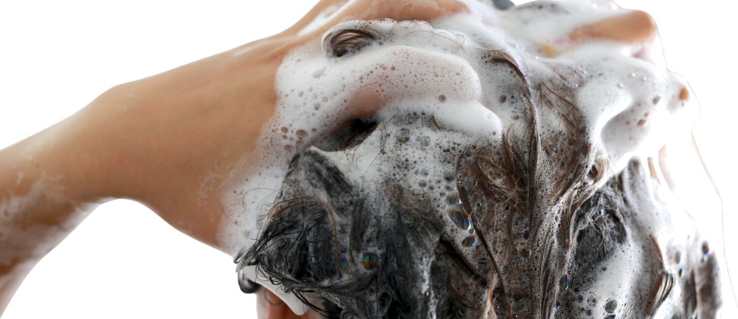 persona che si sta lavando i capelli con. schiuma in testa